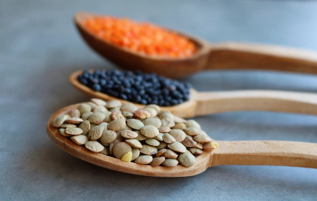 Wooden spoons holding lentils and pantry ingredients