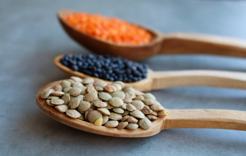 Wooden spoons holding lentils and pantry ingredients