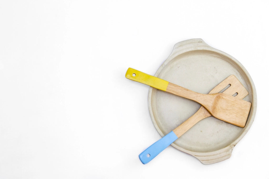 Two wooden spatulas resting on a pale ceramic plate