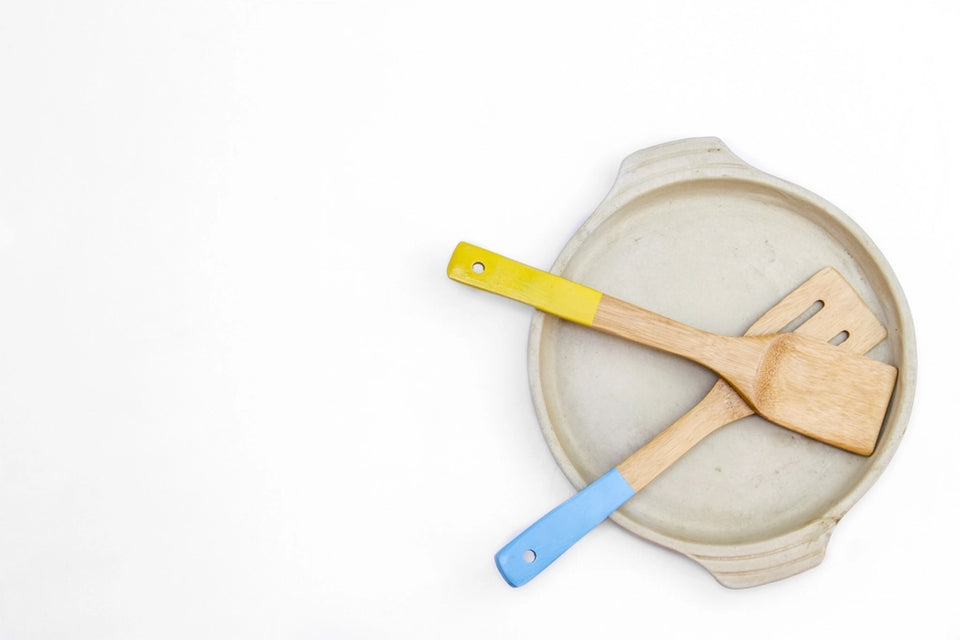 Two wooden spatulas resting on a pale ceramic plate